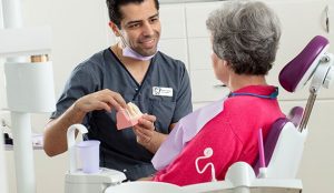 Tandläkare visar en modell av en tand för en patient